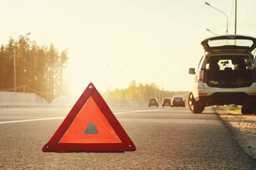 Broken car on the side of the highway and an emergency stop sign