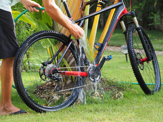 Fototapeta na wymiar A man washes a mountain bike in the backyard.