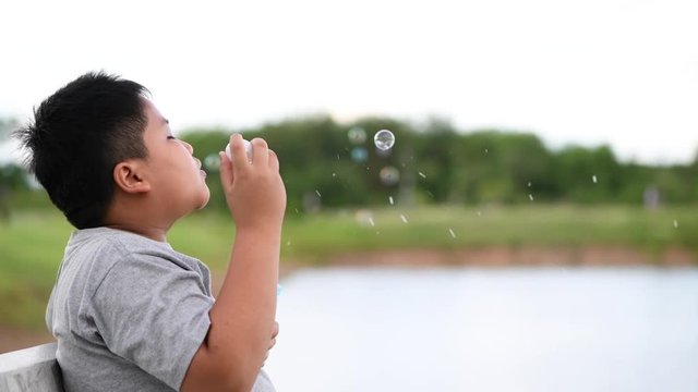 Obese fay boy blowing the soup bubbles close up. The child is having fun outdoors, Summer leisure
