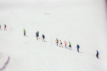 Unidentified people walk along the slope at a ski resort during an active holiday. Trekking and skiing concept. Copyspace