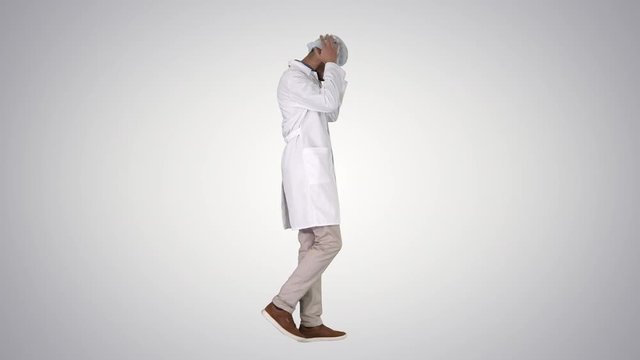 Arabic doctor walking and putting medical cap on on gradient background.