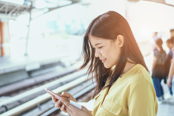 Fototapeta premium Young happy woman holding the smartphone with the train tickets. The concept of online purchase and booking of tickets for travel using the site or application