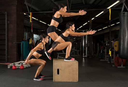 Sporty woman jumping on box training at the gym
