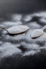 Raw powdered baking soda in a antique spoon on wooden surface along with some more in a plastic...