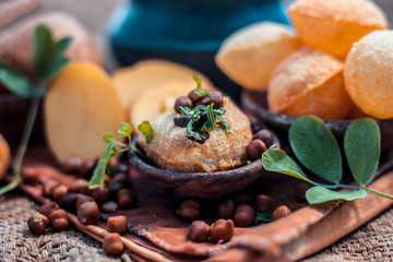 Famous Indian & Asian street food dish i.e. Panipuri snack in a clay bowl along with its flavored...