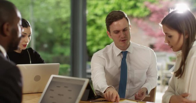 4K Unhappy businessman having a disagreement with colleagues in a meeting. Slow motion.