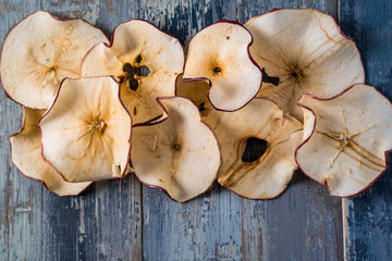 Dried apple chips over blue wooden background with copy space.