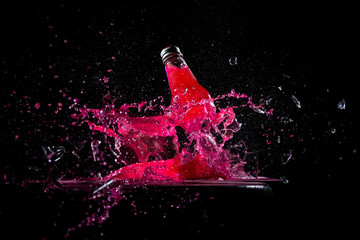 red water glass bottle got shot and explosion splash fracture in dark background for energy drink...