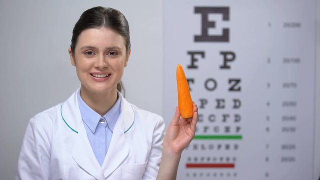 Friendly oculist recommending carrot for maintaining good vision, healthy food