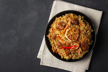 Uzbek pilaf or plov from rice and meat in a cast iron pan. Top view vith copy space.