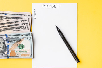 Planning budget concept. Notepad with word budget and dollar bills on a yellow