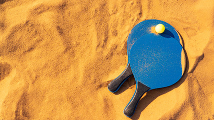 blue rackets and green ball on golden sand beach tennis badminton background