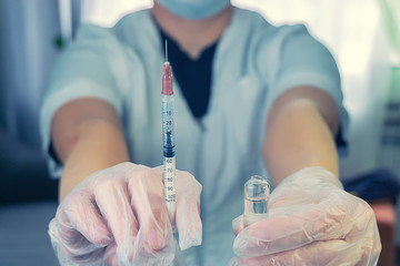 a woman in a white coat with a syringe in hand