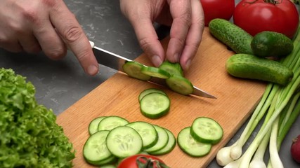 Man cutting cucumber on the wooden desk. Vegetables and healthy food concept