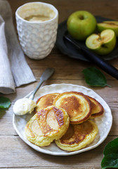 Homemade apple fritters with sour cream, coffee and green apples on a wooden background. Rustic style.