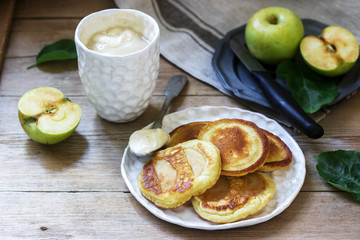 Homemade apple fritters with sour cream, coffee and green apples on a wooden background. Rustic style.