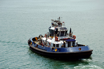 Tugboat assisting to the cargo ship during berthing operation in the port of Cristobal, Panama. 