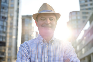 Senior hispanic man in hispanic hat with mustache looking at camera smiling in city centre. Horizontal shape