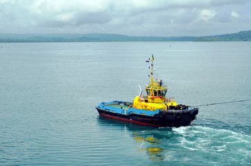 Tugboat assisting to the cargo ship during berthing operation in the port of Cristobal, Panama. 