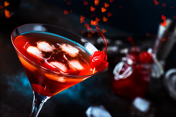 Classic alcoholic cocktail Manhattan with bourbon, red vemuth, bitter, ice and cocktail cherry in glass, gray bar counter background, place for text, selective focus
