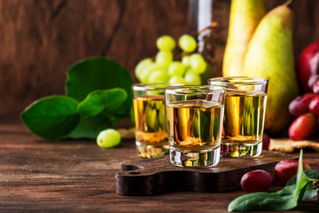 Rakija, raki or rakia - Balkan strong alcoholic drink brandy type based on fermented fruits, vintage wooden table, still life in rustic style, place for text