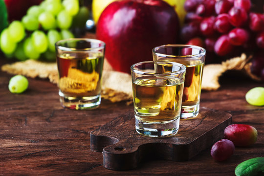 Rakija, raki or rakia - Balkan strong alcoholic drink brandy type based on fermented fruits, vintage wooden table, still life in rustic style, place for text