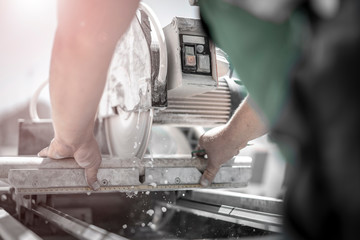 Gartenbauer schneidet Steinplatte mit großer Steinsäge mit Wasserkühlung
