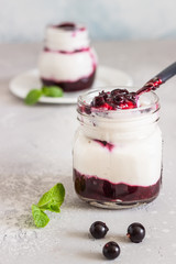 Jars of natural yogurt with berry sauce and mint on light grey table. Healthy eating. Copy space. Summer food concept. 