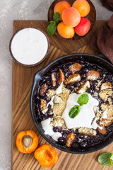 Crumble in cast iron pan with blackcurrant and apricot served with natural yogurt and min. Healthy food concept. 