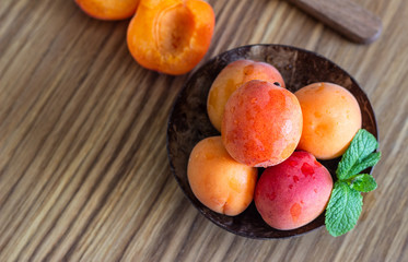 Naklejka na ściany i meble Delicious ripe apricots in a wooden bowl on a wooden cutting board. 