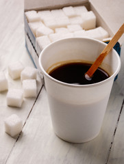 coffee in a paper cup and a pack of sugar