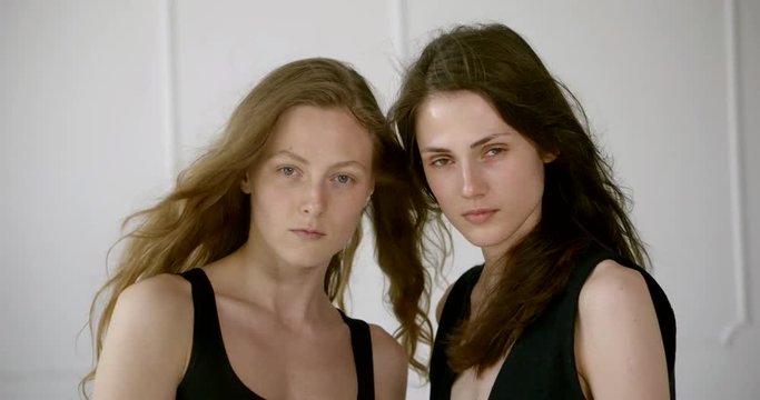 portrait of two girls models close-up. One is light and one is dark. They're posing.