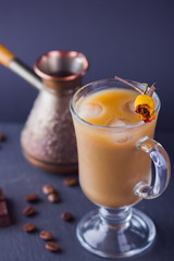 Copper coffee pot (Cezve) and coffee beans. Coffee with milk on dark background. Latte and black chocolate on slate board. Milk drink in glass beaker and dried rose