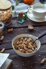Bowl with home made granola and spoon on brown wooden table background, healthy breakfast concept, cereal granola food with nuts seed organic muesli morning diet oat meal for health vertical view