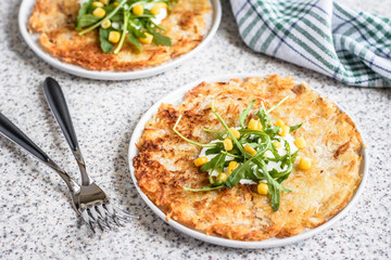 Potato rosti with corn and rocket salad served on a gray background. Traditional swiss dish