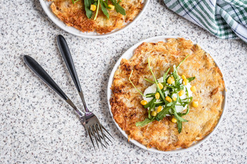 Potato rosti with corn and rocket salad served on a gray background. Traditional swiss dish