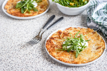 Potato rosti with corn and rocket salad served on a gray background. Traditional swiss dish