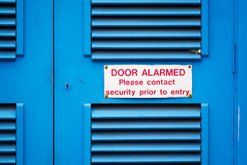 Door alarmed contact security before entry sign on blue boiler room door