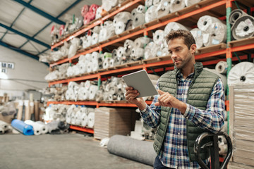 Warehouse worker using a digital tablet to check stock