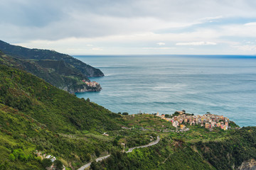 Manarola village with Riomaggiore in the distance, as seen from the hiking trail above. Picturesque Cinque Terre landscape in Italy.