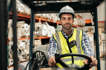 Smiling forklift driver moving stock on a warehouse floor
