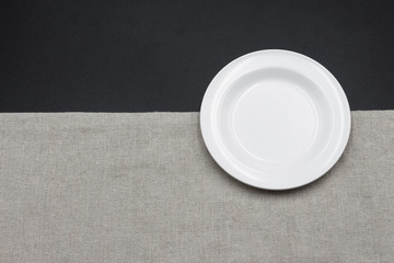 Obraz na płótnie Canvas A white empty plate is quietly placed on the right side of the black and white background, used as a background for the table material.