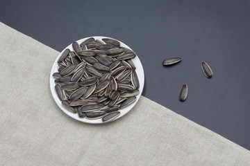A simple background image of a small plate of sunflower seeds and white linen, food dish background