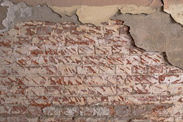 Old brick wall with peeling colorfull plaster. On the need to think about urgent repairs, reconstruction or new construction. Or vintage background.