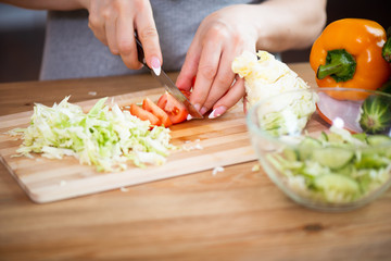 cooking, food and concept of veganism, vigor and healthy eating - close up of female hand cutting vegetables for salad