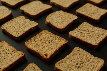  A bunch of bread toast on a black background. Healthy nutrition, diet. Rye, oats, buckwheat, integral bread toast. Pattern and background bread toast concept. 
