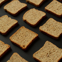  A bunch of bread toast on a black background. Healthy nutrition, diet. Rye, oats, buckwheat, integral bread toast. Pattern and background bread toast concept. 