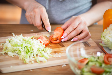 cooking, food and concept of veganism, vigor and healthy eating - close up of female hand cutting vegetables for salad