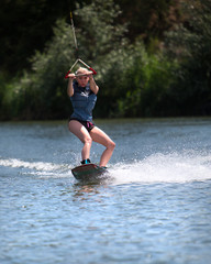 Young pretty slim woman riding wakeboard in summer