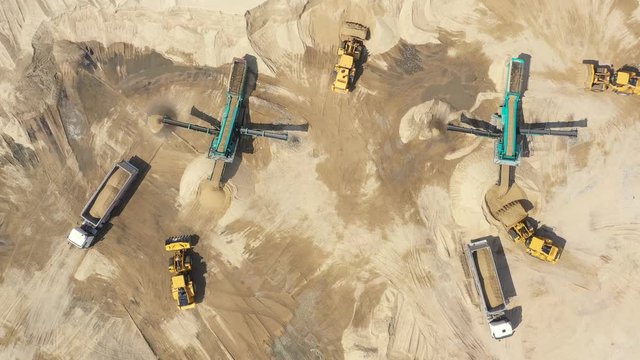 Aerial view, machinery working at clay quarry, heavy loaders, large trucks, bulldozers, excavators, Sand quarry, Mining, Truck takes raw materials from the quarry, Large clay warehouse